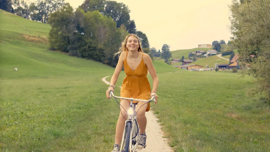 Girl on a bicycle, smiling.